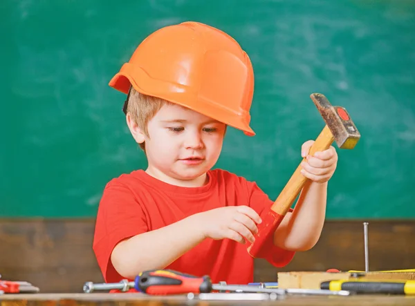 Gyerek játék-val szerszámok. Narancs bukósisak és javítások a műhelyben a tábla mögött ülve piros póló fiú — Stock Fotó