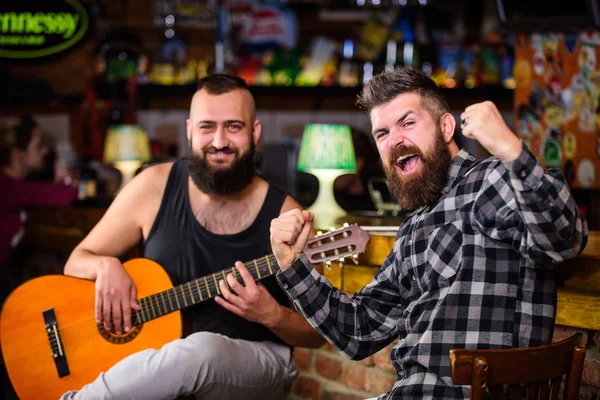 Live music concert. Man play guitar in pub. Acoustic performance in pub. Hipster brutal bearded with friend in pub. Cheerful friends sing song guitar music.