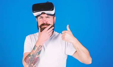 Sakal ve bıyık Vr gözlük, mavi arka plan ile olan adam. VR teknolojisi kavramı. Vr gözlüklü, baş ekran monte. Hipster düşünceli yüzünde göstermek jest yaşasın