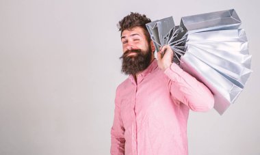 Hippi üzerinde yüz alışveriş göz kırpıyor. Alışveriş kavramı. Adam alışveriş satış sezonu üzerinde omuz grup taşır. Sakal ve bıyık tutan alışveriş torbaları, gri arka planı olan adam