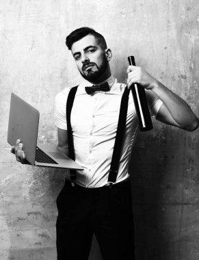 Ciddi yüzlü, gri bilgisayar ve alkollü bir adam.