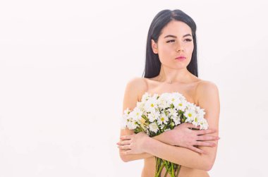 Sağlıklı ciltle pürüzsüz kadınla çekici görünüyor. Doğal kozmetik kavramı. Bayan göğüsler üzerinde beyaz izole çiçekli kapsar. Papatya çiçeği göğüsler önünde sakin yüz çıplak kız tutar