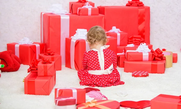 Моё первое Рождество. Делиться радостью первого Рождества с семьей. Первое рождество ребенка раз в жизни. Подарки для первого ребенка. Маленький ребенок играет рядом с кучей упакованных красных подарочных коробок — стоковое фото