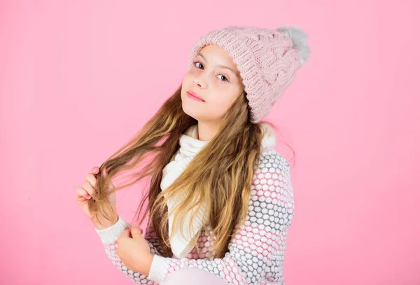 Tips for caring for knitted garments. Child long hair warm soft woolen hat enjoy softness. Kid girl wear knitted soft hat pink background. Keep knitwear soft after washing. Soft knitted accessory