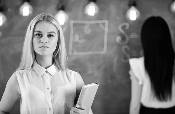 Estudante, professor em stand de desgaste formal em sala de aula. Conceito de alunos e estagiários. Mulheres atraentes preparando-se para a aula. Menina parece confiante enquanto senhora escrevendo no fundo quadro, desfocado — Fotografia de Stock