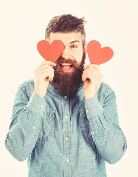 Homem com barba no amor detém corações vermelhos, cobre os olhos . — Fotografia de Stock