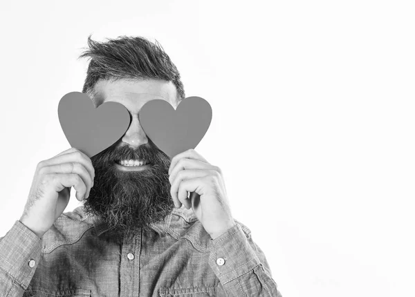 Homem com barba segura corações de papel vermelho como óculos . — Fotografia de Stock
