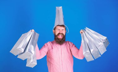 Pembe gömlek ve mavi arka plan üzerinde izole kafasında gümüş çanta trendy sakallı adam. Alışveriş şampiyon kazanan ilk ödül yarışması, mutluluk kavramı. Adam zevk satış zaman sakallı