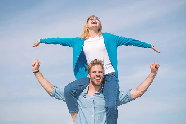 Couple in love enjoy feeling freedom outdoor sunny day. Couple happy date having fun together. Lovers enjoy date and feeling free. Freedom concept. Man carries girlfriend on shoulders, sky background