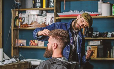 Hipster istemci taze saç kesimi veya saç modeli ile. Styling saç balmumu ile sakallı istemcisinin eller tarafından berber. Berber kavramı. Adam sakal ve bıyık salonların sandalye, arka plan raflarda