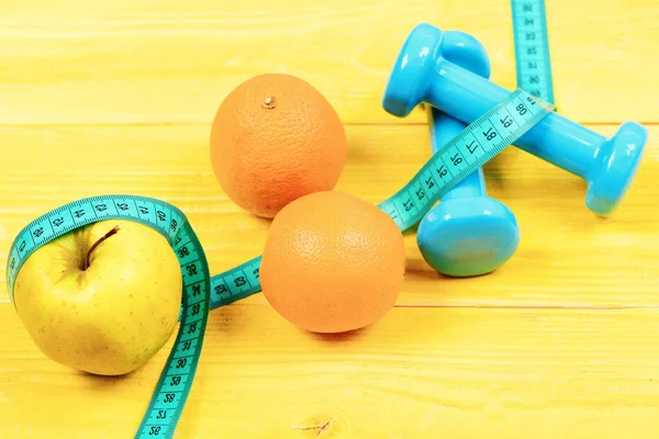 Exercise concept, dumbbells weight with measuring tape, orange and apple — Stock Photo, Image