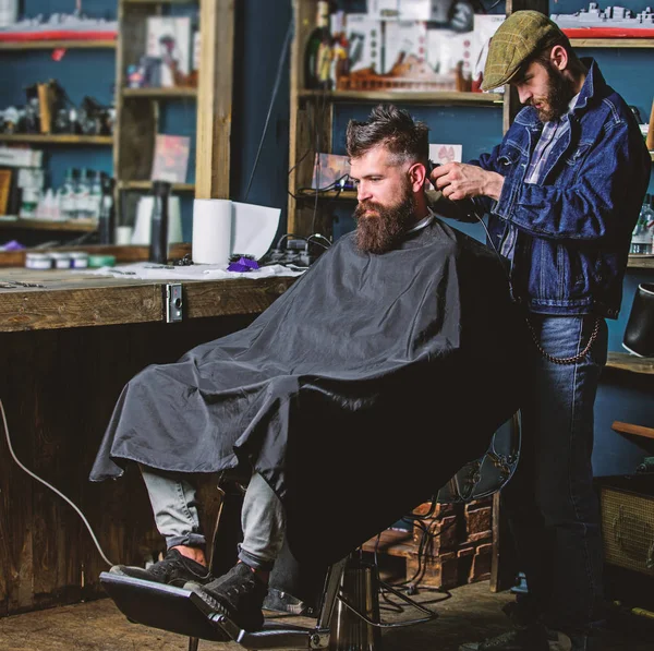 Friseur mit Haarschneidemaschine arbeitet am Haarschnitt des bärtigen Typen Barbershop Hintergrund. Hipster-Klient bekommt Haarschnitt. Friseur mit Haarschneidemaschine am Nacken des Kunden. Hipster-Frisurenkonzept — Stockfoto