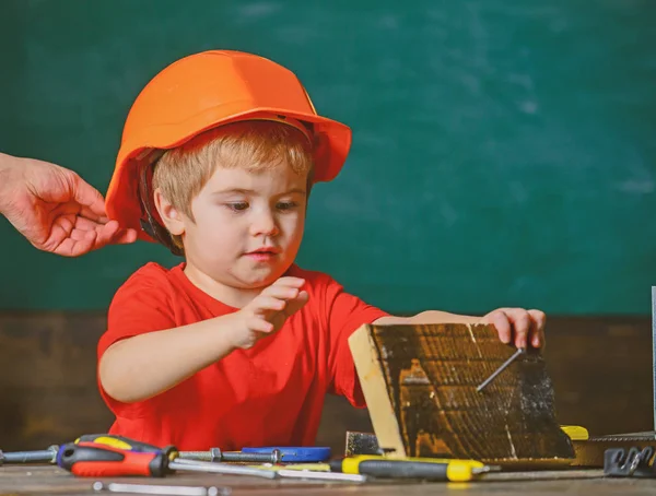 Protection and safety concept. Carefully protect kid with helmet. Toddler in protective helmet at workshop. Child cute and adorable play with wood and screw while male hand putting hard hat on head — Stock Photo, Image