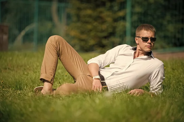 Businessman in sunglasses on sunny outdoor. Man relax on green grass. Handsome macho enjoy summer day. Fashion style and trend. Break time concept — Stock Photo, Image