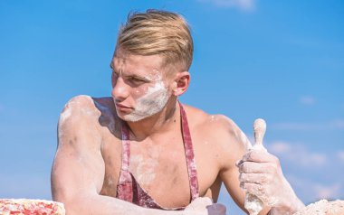 Önlük, gökyüzü arka plan üzerinde..... .adam sarı saçlı sıkı yüzündeki kullanıyor. Cook seksi gövde ile oklava, vücut ve un ile kaplı yüz tutar. Şef aşçı pişirme için hamur hazırlanıyor. Şef kavramı