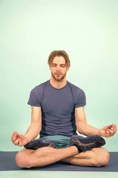 Man meditate on yoga mat. Sportsman relax in lotus pose. Fashion athlete practice yoga in gym. Meditation for body and mind health. Meditation or zen and peace concept