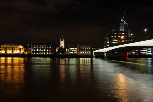 Skyline uitzicht vanaf de rivier op de donkere hemel in Londen, Verenigd Koninkrijk. Stad en brug met nacht verlichting. Gebouwen reflectie op het water met mooie architectuur. Structuur en ontwerp. Reizen en reis — Stockfoto
