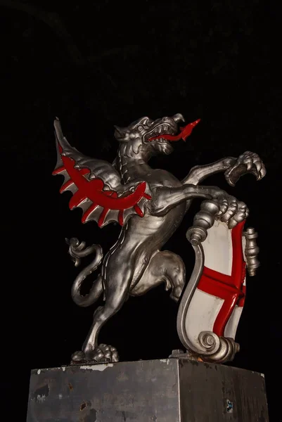 Dragon statue in London, United Kingdom. Dragon with shield on dark sky at night. Coat of arms. Famous tourist attraction. Art and design concept