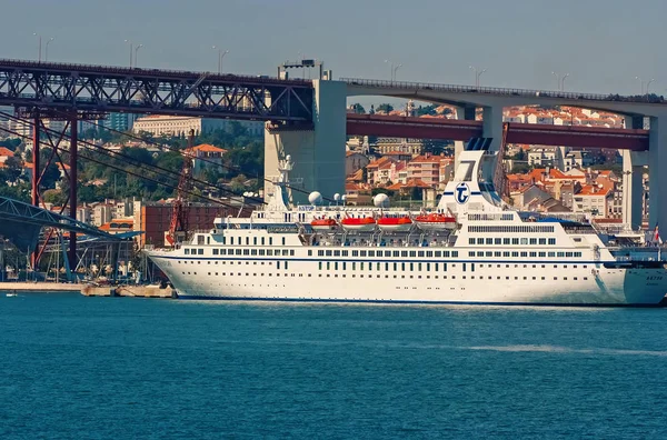 Лиссабон, Португалия - 03 апреля 2010 г.: океанский лайнер в морском порту. Корабль на воде под мостом в солнечный день. Водное судно в голубом море. Путешествовать по воде. Мбаппе на летних каникулах — стоковое фото