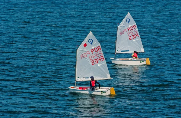 Lisabon, Portugalsko - 03 duben 2010: jachty v modré moře. Děti sportovci se účastní závodu na slunečný den. Mistrovství republiky v jachtingu moře. Regatta a jachtě plující sport. Cestování po vodě s dobrodružství — Stock fotografie