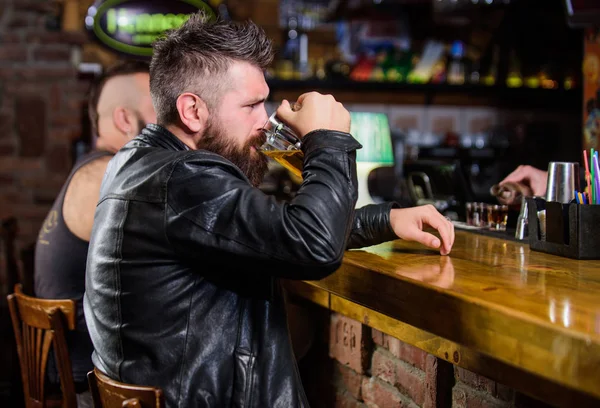 Order alcohol drink. Bar is relaxing place have drink and relax. Man with beard spend leisure in dark bar. Hipster relaxing at bar with beer. Brutal hipster bearded man sit at bar counter drink beer