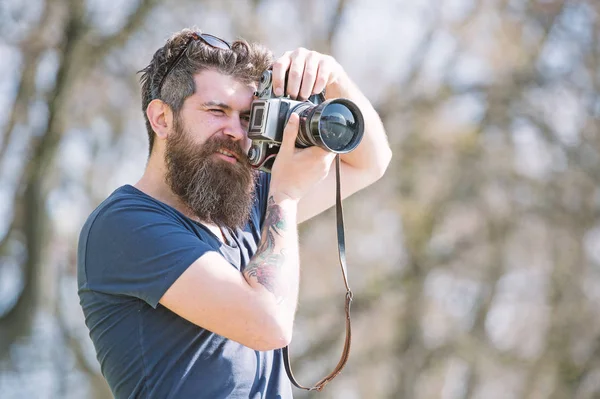 Joven fotógrafo masculino tomando fotos en el parque con cámara vintage, hobby y concepto de actividad de ocio. hipster barbudo en busca de mejor lugar para la sesión de fotos —  Fotos de Stock