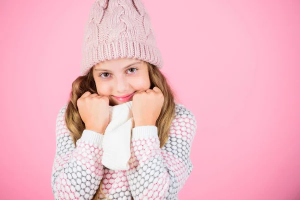 Winter fashion warm clothes concept. Warm accessories that will keep you cozy winter. Child long hair warm woolen hat enjoy warm and softness. Kid girl wear knitted warm hat relaxing pink background