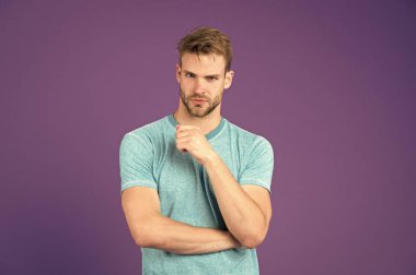 Mor zemin üzerine mavi tshirt atletik bir adam. Tıraşsız yüzü deri mor zemin üzerinde sakallı adam. Moda şık saç modeliyle. Cilt Bakımı ve Kuaför Salonu. Spor ya da fitness ve sağlıklı yaşam