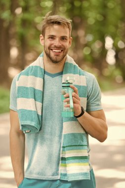 Adam atletik görünümlü şişe su ile tutar. Spor ve sağlıklı yaşam konsepti. Adam atlet açık eğitim sportif giysiler içinde. Sporcu eğitim Stadyumu'nda güneşli bir gün sonra su iç