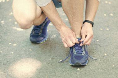 Koşu için hazırlanıyor. Ayakkabı bağcığı spor ayakkabı, yol arka plan ipe eller. Ayakkabı bağcığı sportif spor ayakkabı bağlama pedometer ile sporcu elleri. Ekipman kavramı çalıştırıyor. Erkek eller tarafından bağlama ayakkabı bağcığı