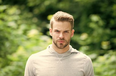 Adam sakallı ve çekici görünümü ile ilgili umurunda değil. Kıl defocused ciddi bir yüz, yeşil doğa arka plan üzerinde olan adam. Metroseksüel kavramı. Adam sakal veya tıraşsız adam yakışıklı ve serin görünüyor