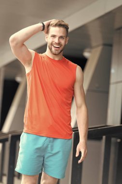 Sportif giyim, kentsel arka yüzüne gülümseyerek üzerinde kıl olan adam. Spor moda kavramı. Sakal veya şık spor giysileri tıraşsız adam olan adam. Adam sakallı ve çekici moda hakkında umurunda değil.