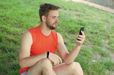 Spor araç konsepti. Atlet fitness izci veya adım sayar. Adam atlet fitness İzleyicisi ile akıllı telefon app, Doğa arka plan kurma meşgul yüz. Sporcu pedometre gadget ile eğitim