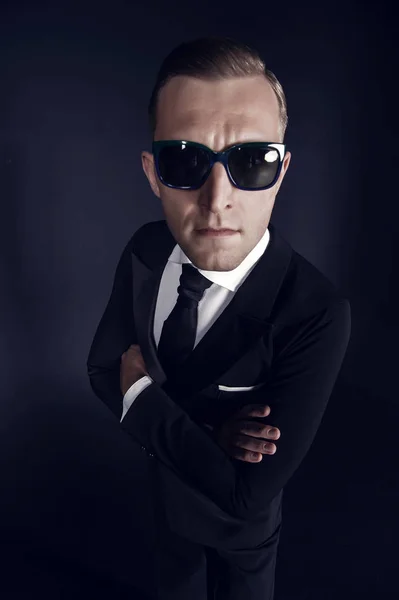 Homem de negócios em terno preto e óculos de sol no fundo escuro — Fotografia de Stock