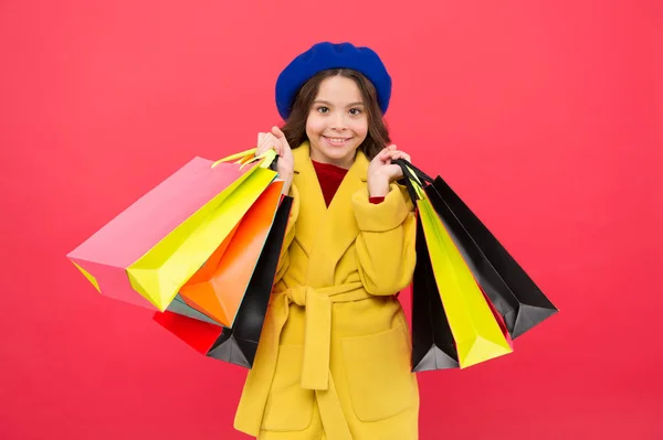 Dziewczyna słodkie dziecko trzymać tło czerwone torby na zakupy. Rabat handlowe na urodziny wakacje. Fashionista Uwielbiam zakupy. Obsesję na punkcie zakupów. Dostać odświeżania głównych szafa z wiosennej wyprzedaży w sklepach — Zdjęcie stockowe