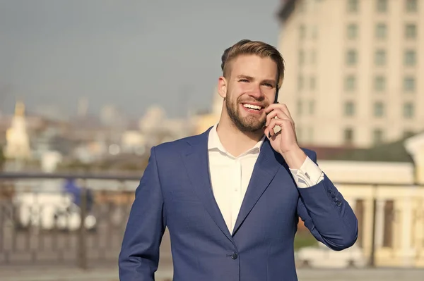 Affärslivsstilsbegreppet. Glad affärsman med smartphone på solig terrass. Man ler i formell kostym med mobiltelefon utomhus. Företagskommunikation och ny teknik — Stockfoto