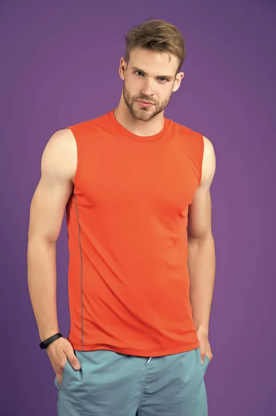 Confident sportsman. Man handsome sports clothing violet background. Athlete sportsman confident puts hands into pockets. Masculinity and confidence concept. Sportsman with fitness band smart watch