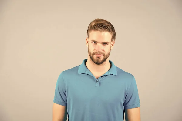 Mens beleza, moda e estilo. Homem de tshirt azul sobre fundo cinzento. Um tipo com a cara barba por barbear. Macho com cabelo loiro e corte de cabelo elegante. Cuidado do cabelo no salão ou barbearia — Fotografia de Stock