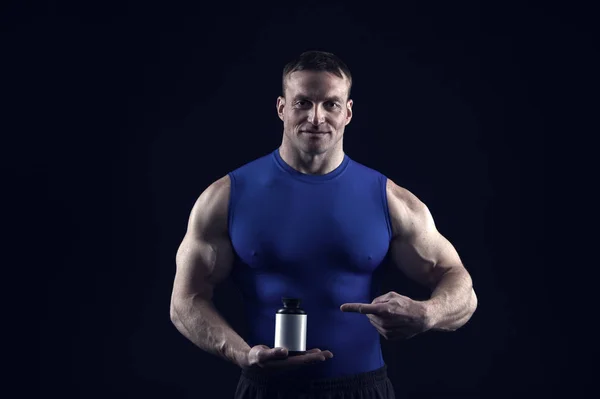 筋肉のついた体とハンサムなボディービルダー男保持するステロイドの薬瓶 — ストック写真