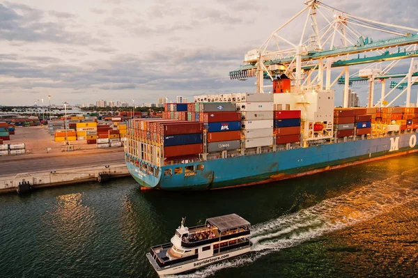 Miami, EUA - 01 de março de 2016: navio de carga e barco de recreio no porto de contêineres marítimos. Porto ou terminal marítimo com contentores e guindastes no céu nublado. Conceito de negócios e férias — Fotografia de Stock