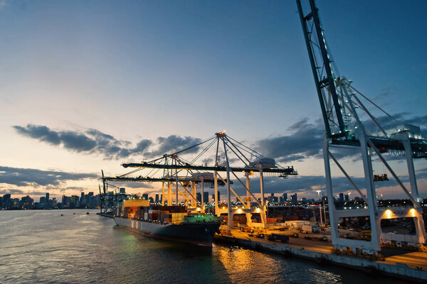 cargo ship and cranes in sea port on evening sky. Maritime container port or terminal. Shipping freight and merchandise. Water transport and transportation concept