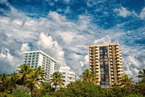 Casas en el cielo nublado en Miami, EE.UU. Edificios de apartamentos u hoteles en jardín con palmeras verdes. Arquitectura y bienes raíces en resort tropical. Vacaciones de verano o ansia de viajar. viaje y viaje — Foto de Stock