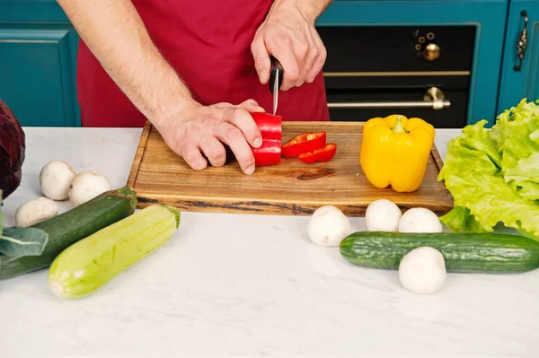 Концепція органічних продуктів. Рука скибочку перець з керамічних ножів. Овочі отримати вирізати на дерев'яні обробна дошка. Приготування їжі та кулінарні рецепти. Вегетаріанське меню та здорова дієта — стокове фото
