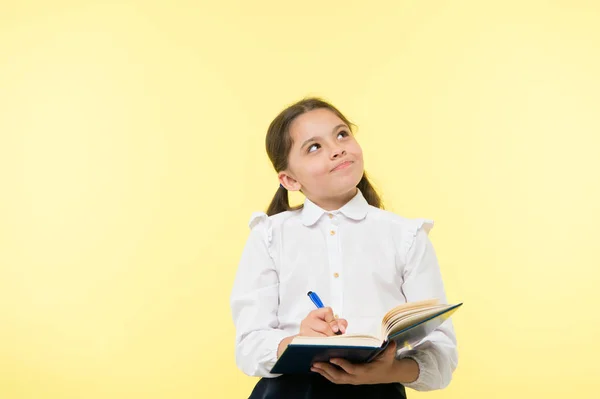 Child school uniform kid doing homework. Child girl school uniform clothes hold book and pen. Girl cute write down idea notes. Notes to remember. Write essay or notes. Personal schedule. Making notes — Stock Photo, Image