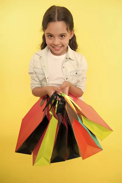 Niña feliz cara sonriente lleva paquetes de racimo fondo amarillo. Concepto de cumpleañera. A la chica le gusta recibir regalos y regalos de cumpleaños. Todo para mí. Niño feliz celebrando cumpleaños con regalos —  Fotos de Stock