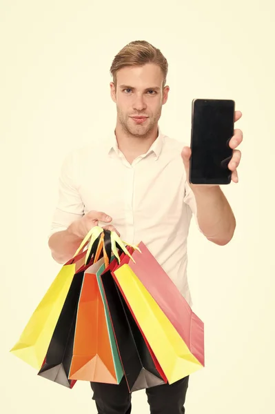 Guy kopen modieuze kleding online met smartphone. Man gelukkig client heeft ontvangen pakketten aankopen. Online winkelen concept. Man neemt voordelen online winkelen. Guy draagt bos kleurrijke tassen — Stockfoto