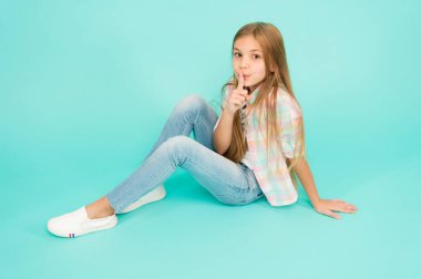 Sessizlik tutmak. Sevimli kız çocuk ağız üzerinde parmak tutmak. Uzun sarı saçlı küçük kız. Rahat tarzı giyen küçük çocuk. Küçük moda model güzellik bakışla. Ayak uydurarak moda kız