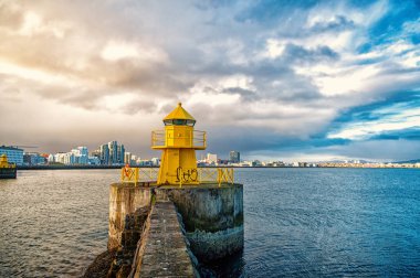 Reykjavik, İzlanda taş iskelede fener kulesi. Deniz feneri. Deniz manzarası ve bulutlu gökyüzü manzarası. Mimari yapı ve tasarım. Seyir yardım kavramı. Yolculuk tutkusu ve seyahat