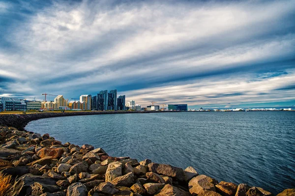 Seascape com costa de pedra em reykjavik, iceland. Construção da cidade no lado do mar. Skyline no céu nublado. Arquitetura e construção. Wanderlust ou viagem e aventura — Fotografia de Stock