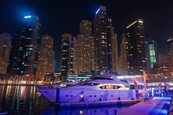 Dubai, Emiratos Árabes Unidos - 26 de diciembre de 2017: club náutico en el distrito de Dubai Marina por la noche. Barco de yate en skyline con iluminación. Transporte y transporte por agua. Viaje o viaje y viaje — Foto de Stock